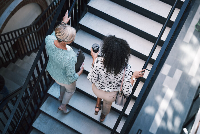 Two women walking down stairs in an office building, illustrating caution and awareness of dangers like powerful water risks.