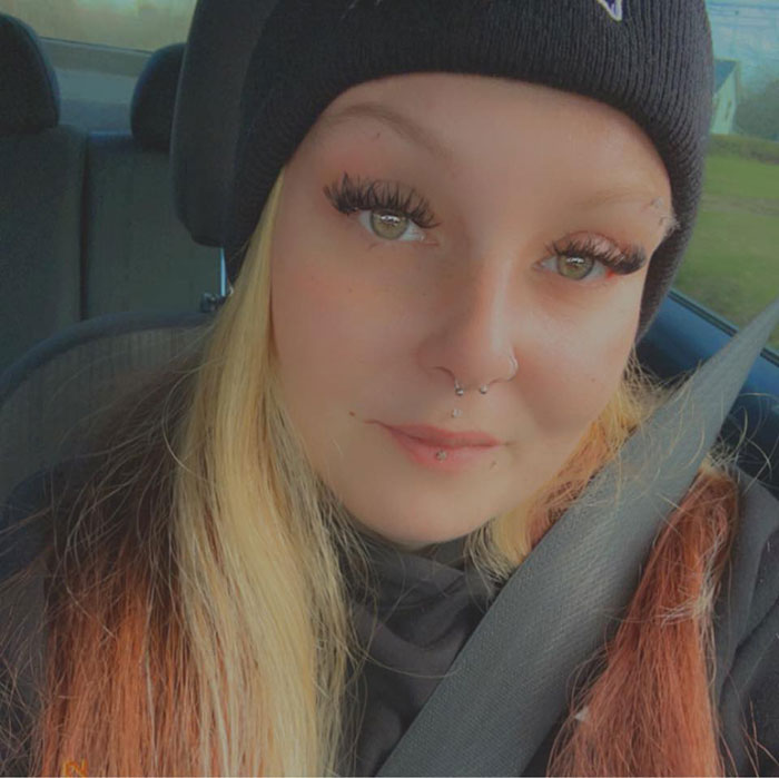 Teen girl in a car wearing a beanie and seatbelt, related to mom allowing name change after bullying over racist name.