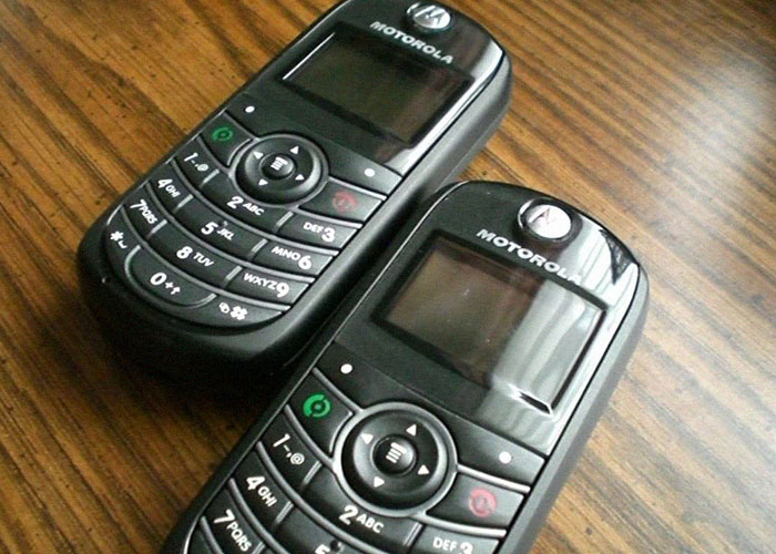 Two outdated Motorola cell phones on a wooden surface illustrating corporate Darwin award for dumb business failures.