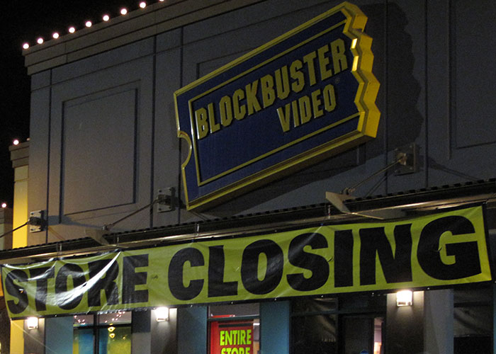 Blockbuster Video store closing with large yellow sign, illustrating companies competing for corporate Darwin award.