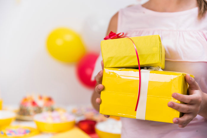 Teen holding yellow birthday gifts at a party, highlighting 13YO refusing to invite one girl from school. Teen holding yellow birthday gifts at a party, highlighting 13YO refusing to invite one girl from school.