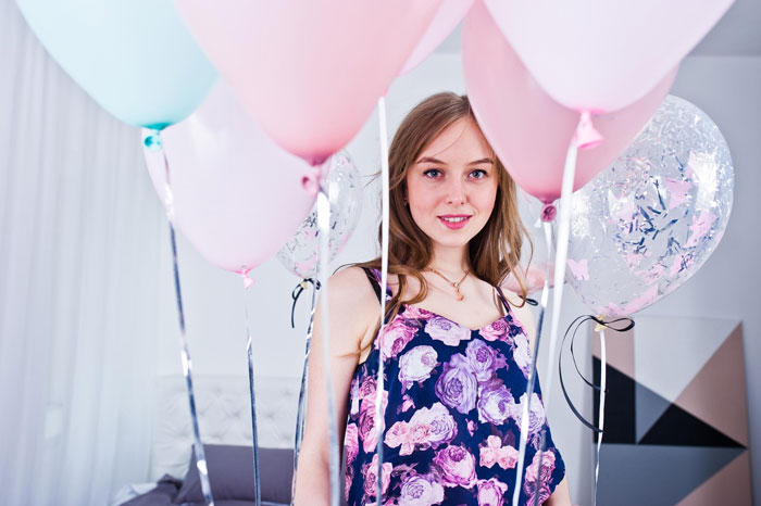 Teen girl surrounded by pink and blue balloons, reflecting 13YO refusal to invite one girl from school story. Teen girl surrounded by pink and blue balloons, reflecting 13YO refusal to invite one girl from school story.