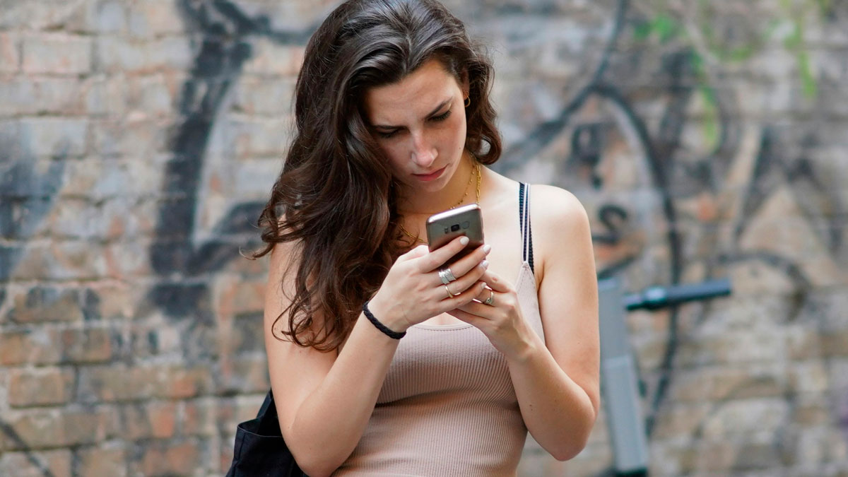 Young woman with long hair looking intensely at her smartphone, showing online behavior and reactions.