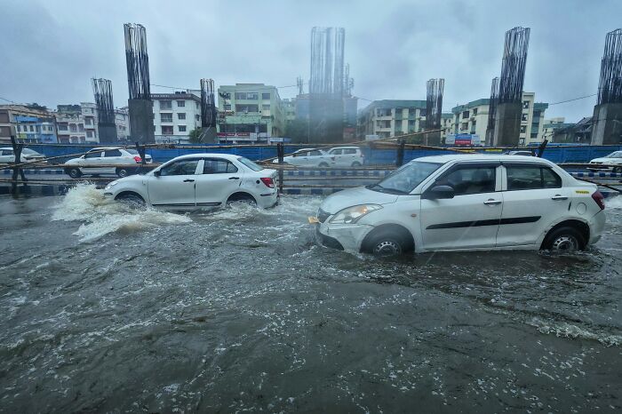 Flooded street with cars struggling through deep water, illustrating uniquely awkward and disastrous situations.