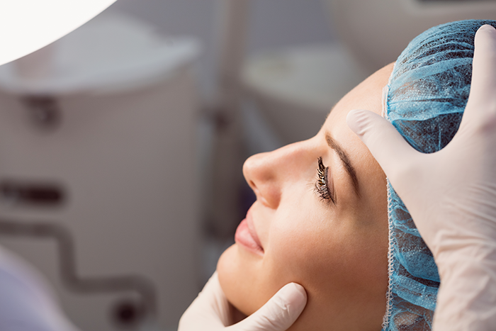 Woman in surgical cap being examined by doctor preparing for plastic surgery in a medical clinic setting. Woman in surgical cap being examined by doctor preparing for plastic surgery in a medical clinic setting.