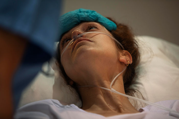 Patient with oxygen tube lying in hospital bed while doctors attend, highlighting times doctors messed up bad in care.