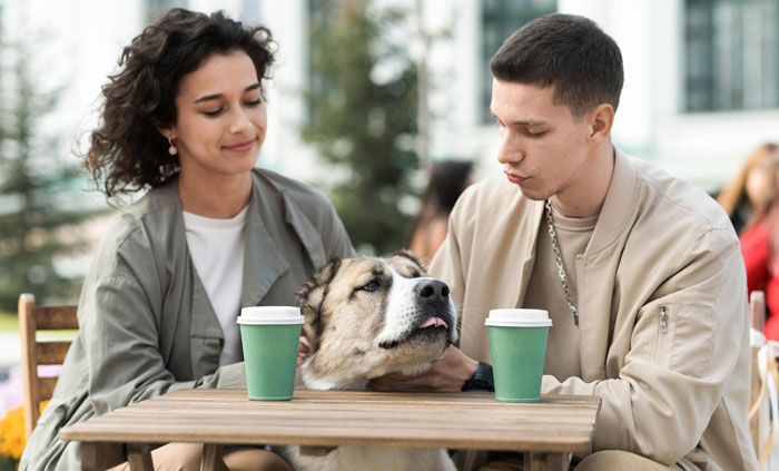Couple sitting at a table with a large dog, highlighting negligent dog owners and dog bite risks to kids. Couple sitting at a table with a large dog, highlighting negligent dog owners and dog bite risks to kids.