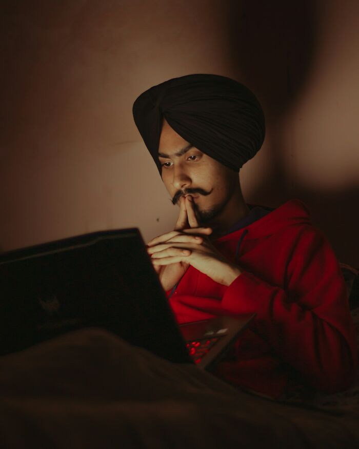 Woman relaxing by pool with laptop in a tropical setting, reflecting positive stereotypes about various countries.