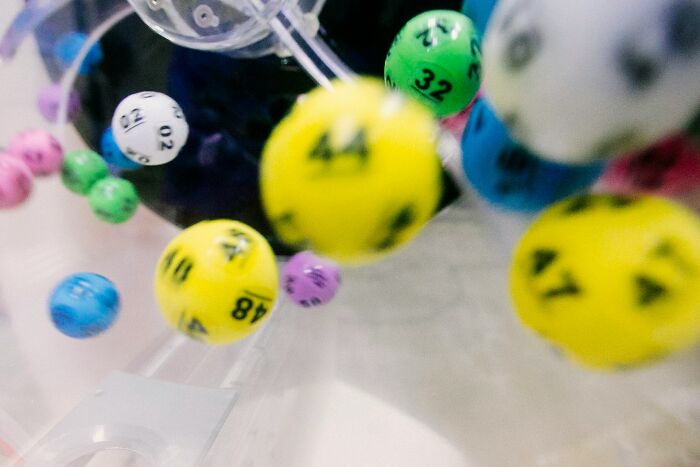 Colorful numbered lottery balls tumbling inside a transparent drum, illustrating uniquely awkward moments.
