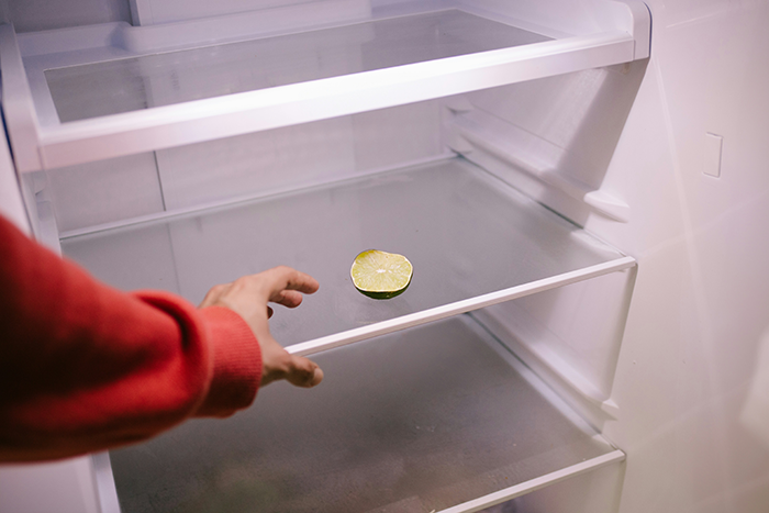 Hand reaching into nearly empty fridge with a single lime, illustrating parenting challenges and kids buying their own food. Hand reaching into nearly empty fridge with a single lime, illustrating parenting challenges and kids buying their own food.