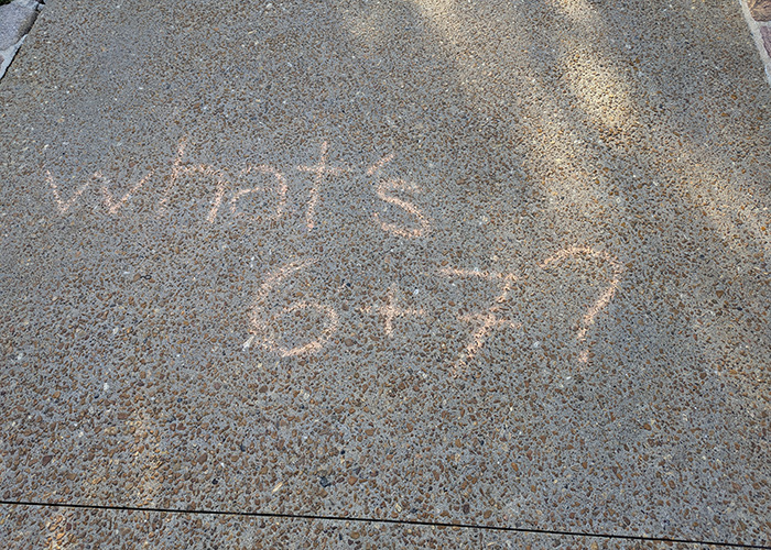 Chalk writing on pavement asking what 6 plus 7 is, referencing the viral 6,7 meme involving Elizabeth Olsen. Chalk writing on pavement asking what 6 plus 7 is, referencing the viral 6,7 meme involving Elizabeth Olsen.