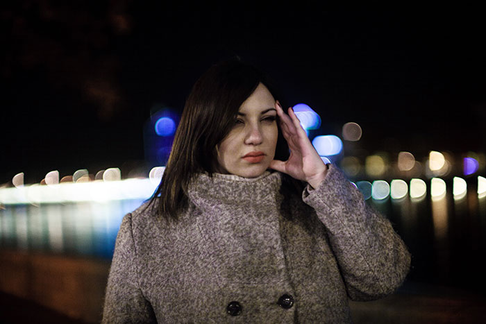 Woman looking stressed outdoors at night with blurred city lights in the background, related to entitled parents haunted hayride topic Woman looking stressed outdoors at night with blurred city lights in the background, related to entitled parents haunted hayride topic
