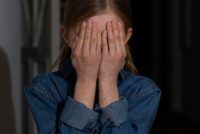 Young girl covering her face in fear during a haunted hayride, reflecting scared kids and entitled parents themes.