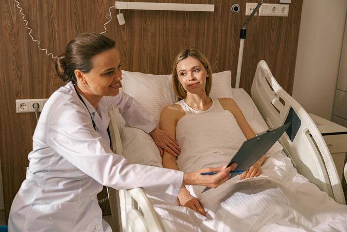 Doctor explaining medical chart to female patient in hospital bed, highlighting Karen patient behavior in ER setting. Doctor explaining medical chart to female patient in hospital bed, highlighting Karen patient behavior in ER setting.