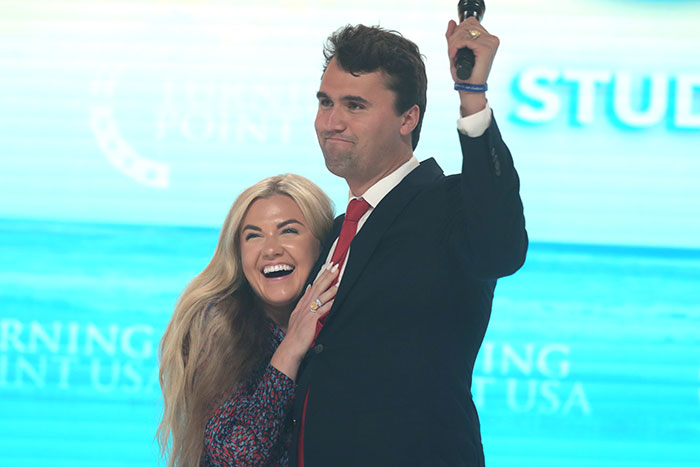 Erika Kirk emotional and JD Vance sharing a moment on stage during a public event with blue background. Erika Kirk emotional and JD Vance sharing a moment on stage during a public event with blue background.