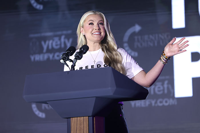 Erika Kirk speaking emotionally at a podium, addressing the viral inappropriate hug with JD Vance in a public event.