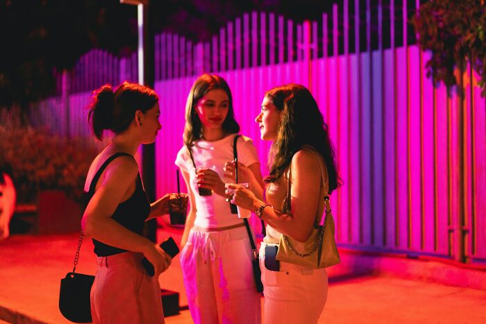 Three young women having a nighttime conversation outdoors, highlighting themes of love, friendship, and broken trust.