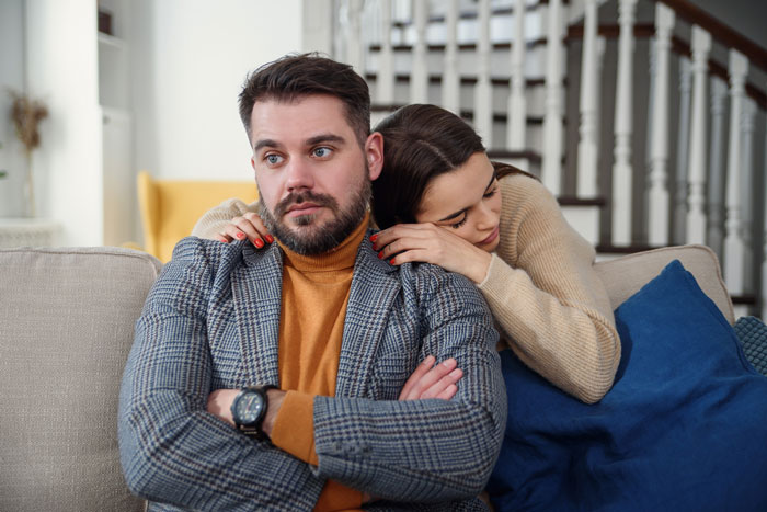Man refusing to visit terminally ill ex-girlfriend who cheated, showing emotional conflict while sitting on a couch at home. Man refusing to visit terminally ill ex-girlfriend who cheated, showing emotional conflict while sitting on a couch at home.