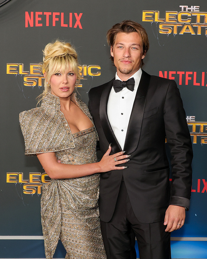 Millie Bobby Brown and Jake Bongiovi posing on the red carpet at a formal Netflix event. Millie Bobby Brown and Jake Bongiovi posing on the red carpet at a formal Netflix event.