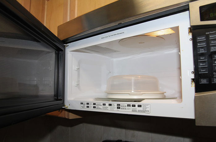 Open microwave oven with a covered plate inside, illustrating unexpected ways lives ended in accidents or mishaps.