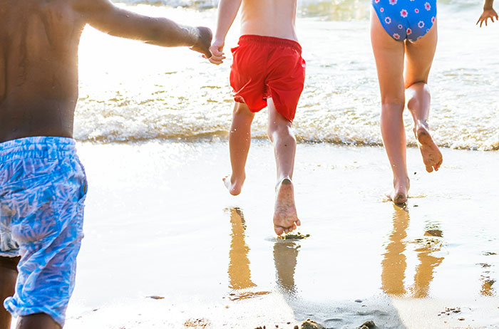Children running on the beach near water, capturing moments of unexpected lives and emotions from real stories.