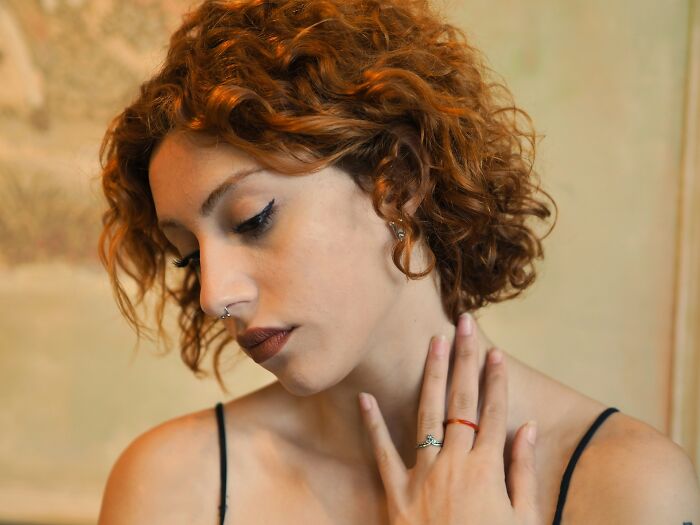 Young woman with curly hair looking down, showing subtle signs of emotional distress related to cheating concerns.