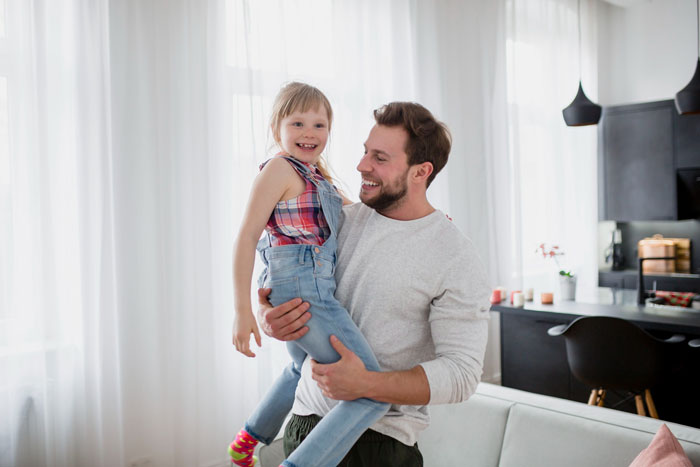 Man smiling while holding daughter indoors, showing fiance babysit daughter hunting family bonding moment. Man smiling while holding daughter indoors, showing fiance babysit daughter hunting family bonding moment.