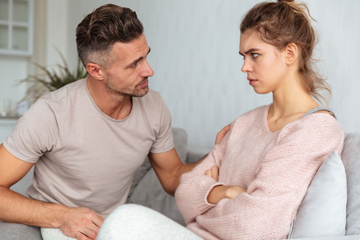 Fiance comforting upset woman on couch during a serious conversation about babysit daughter and hunting plans. Fiance comforting upset woman on couch during a serious conversation about babysit daughter and hunting plans.