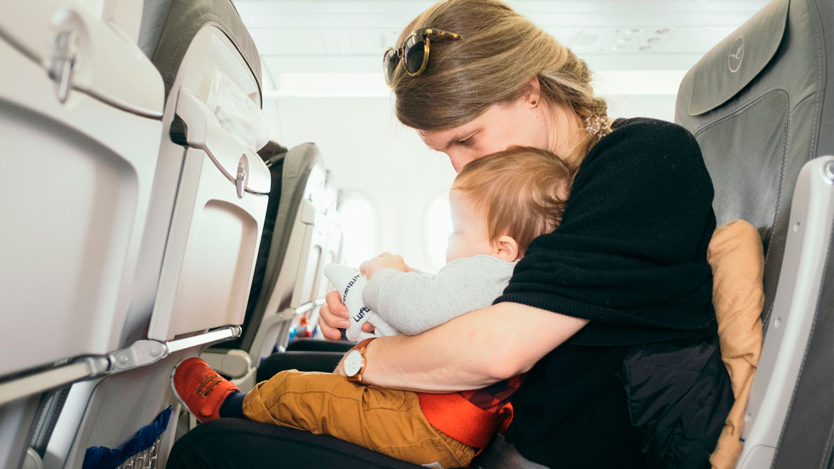 Mother comforting child on airplane, highlighting flight crew and passenger horror stories during travel experience