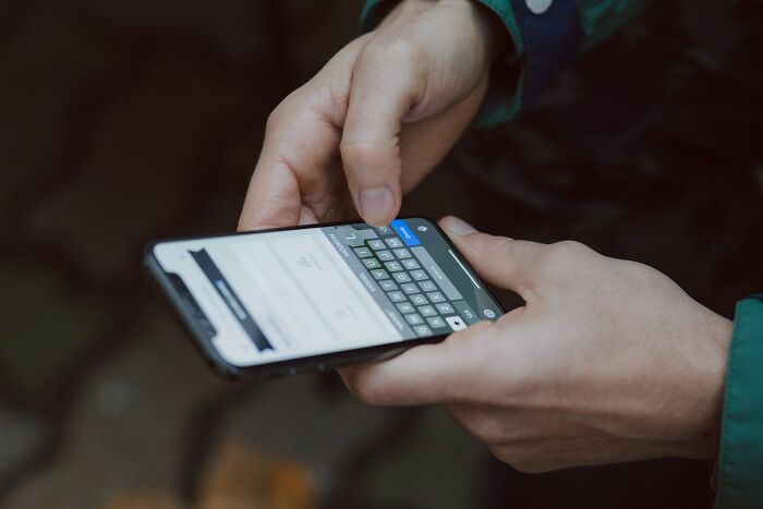 Person holding smartphone and typing a message, illustrating ways people found out their significant other is unfaithful.