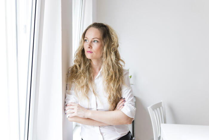 Woman with folded arms looking out window, illustrating disagreement about gifting broken stuff to a friend. Woman with folded arms looking out window, illustrating disagreement about gifting broken stuff to a friend.