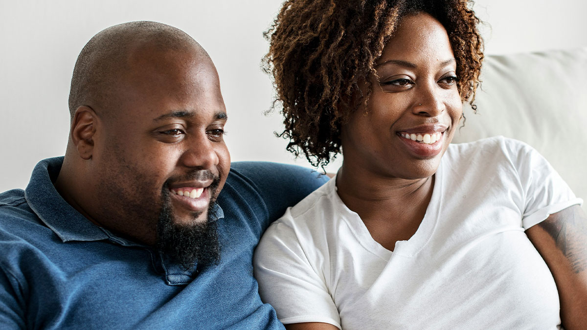 Couple smiling together on couch, illustrating friendship and relationship before trust crumbles over surgery secret exposure.