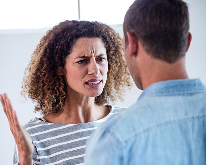 Woman expressing frustration while talking to a man, illustrating a friend who doesn't understand clingy children on vacation. Woman expressing frustration while talking to a man, illustrating a friend who doesn't understand clingy children on vacation.