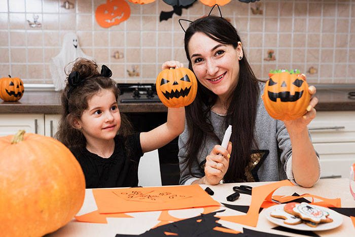 Woman and child carving Halloween pumpkins at home, capturing a holiday moment amidst family tensions. Woman and child carving Halloween pumpkins at home, capturing a holiday moment amidst family tensions.