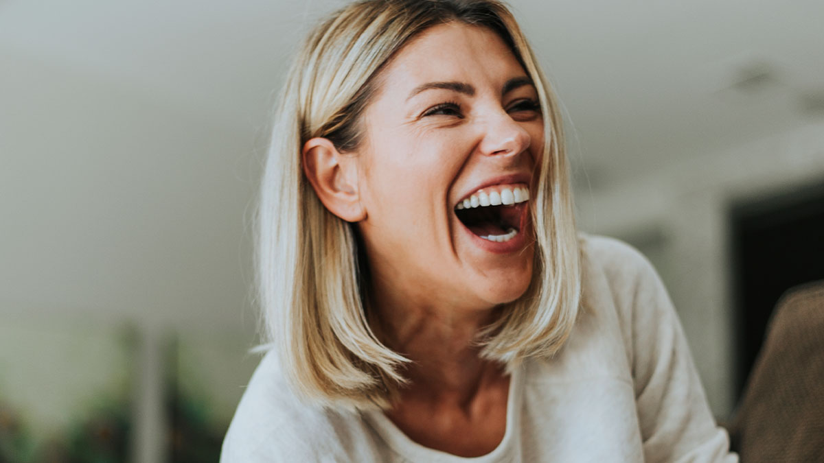 Woman with blonde hair laughing joyfully, capturing a nostalgic moment reflecting on being old now.