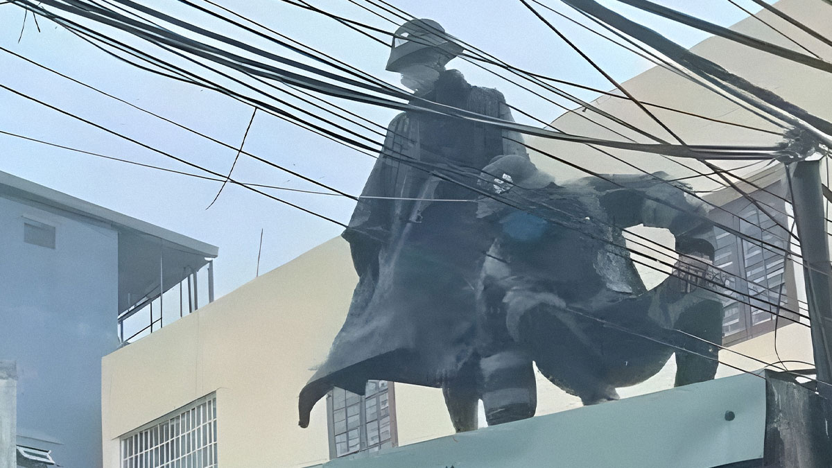 Statue of two figures in dramatic poses on a rooftop with power lines and buildings in the background, pics that go hard.