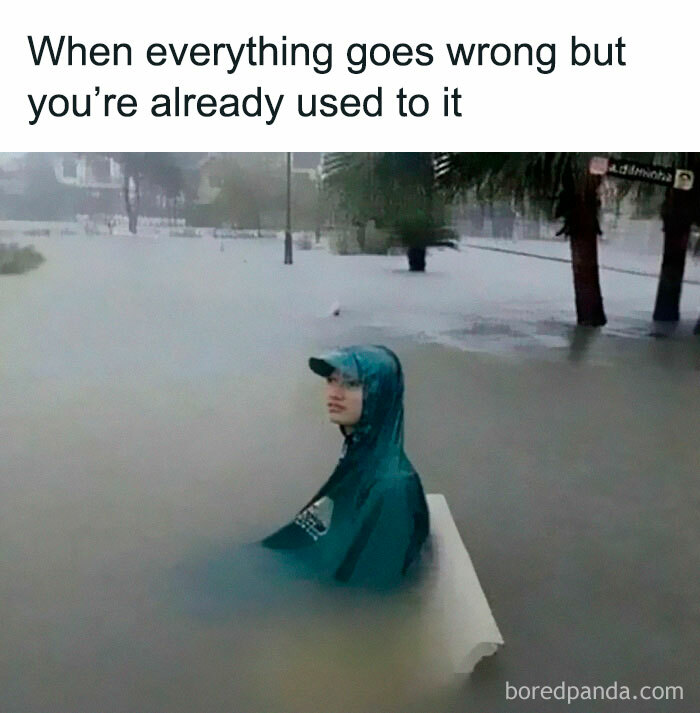 Person wearing a raincoat sitting calmly in floodwater with caption about being used to when everything goes wrong meme.