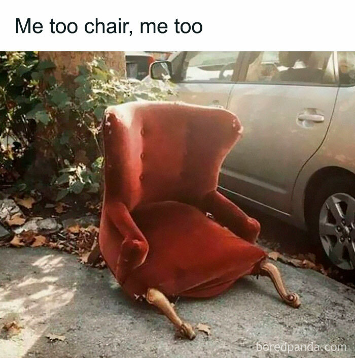 Worn red armchair missing legs sitting on sidewalk next to parked car in funny memes for scrolling.