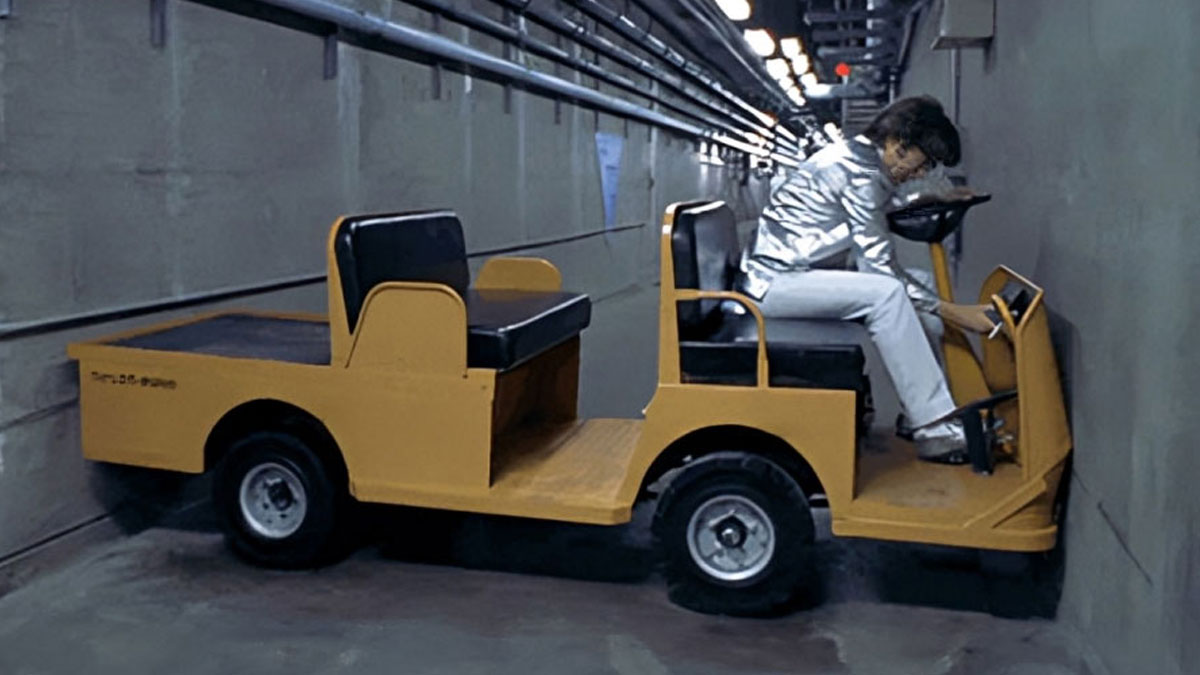 Person in silver jacket stuck driving a yellow cart into a wall, illustrating lack of unique experience meme theme.