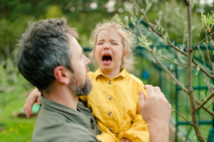 Man holding crying child outdoors, illustrating surprising habits people discovered about their partner after moving in together.