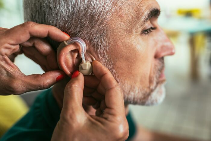 Older man having a hearing aid fitted, illustrating surprising habits and secrets people discovered about their partner after moving in.