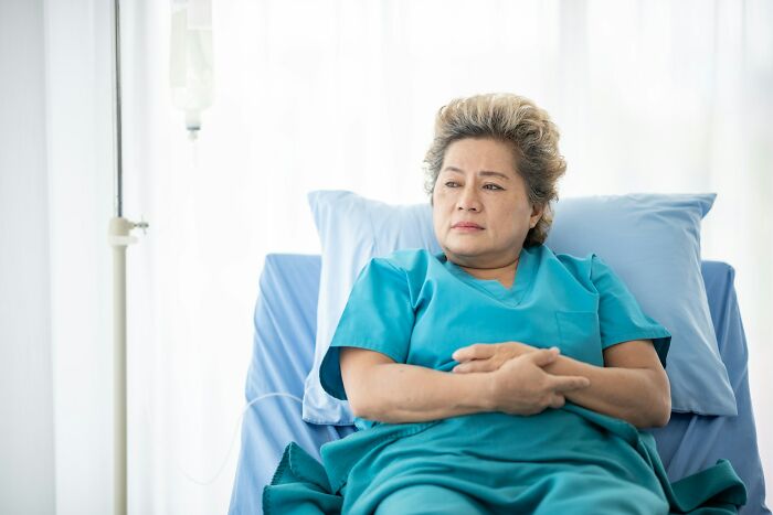 Elderly woman in hospital bed looking thoughtful and concerned, reflecting on heavy confessions and untold stories.