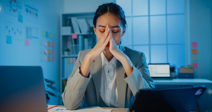 Woman in office deep in thought realizing compulsory things in life may actually be optional during a late work session.