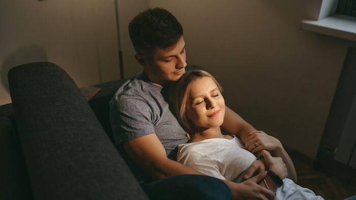 Couple sitting closely on a couch, sharing intimate moments and discovering surprising habits after moving in together.
