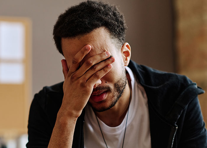 Man covering his face with hand, showing frustration and stress after a mom destroys daughter's happy relationship on a date.