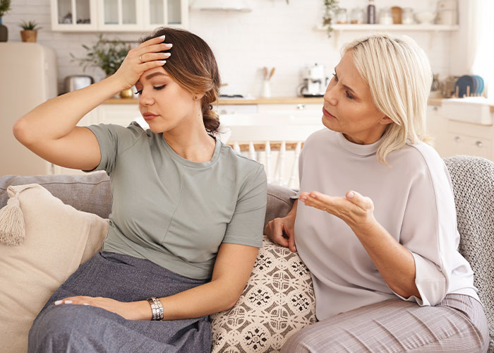 Mother and daughter having a tense conversation on a couch, illustrating mom destroys daughter’s happy relationship after date.