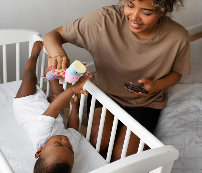 New mom bonding with baby in crib while recovering, highlighting MIL demands for baby’s name honoring her culture.