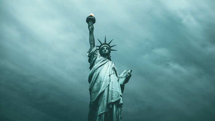 Statue of Liberty sculpture standing tall against a cloudy sky, a spectacular landmark for travel bucket lists.