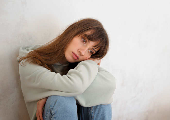 Young woman in casual clothes looking pensive and sad, reflecting on an evil stepmom’s failed life and poetic justice.
