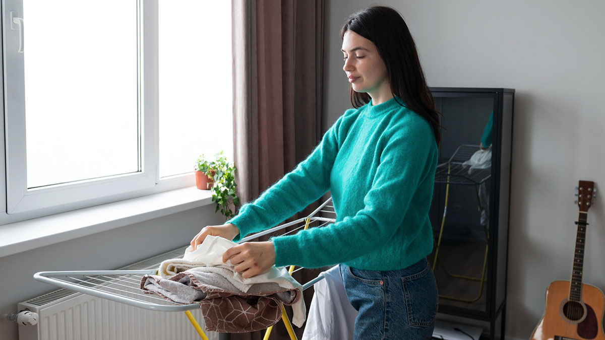 Young woman in a teal sweater doing laundry, representing golden child getting laundry service from parents at home.